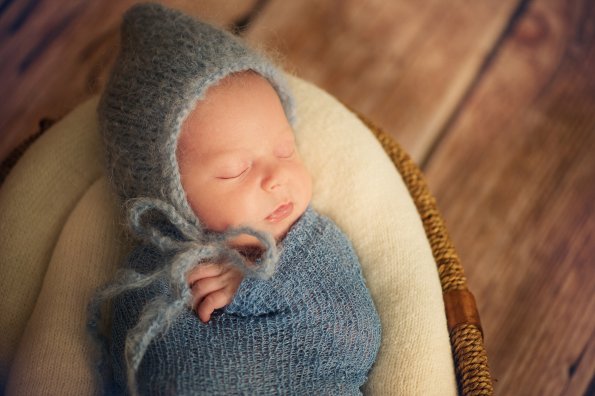 Newborn Baby in Wrap and Hat in Basket